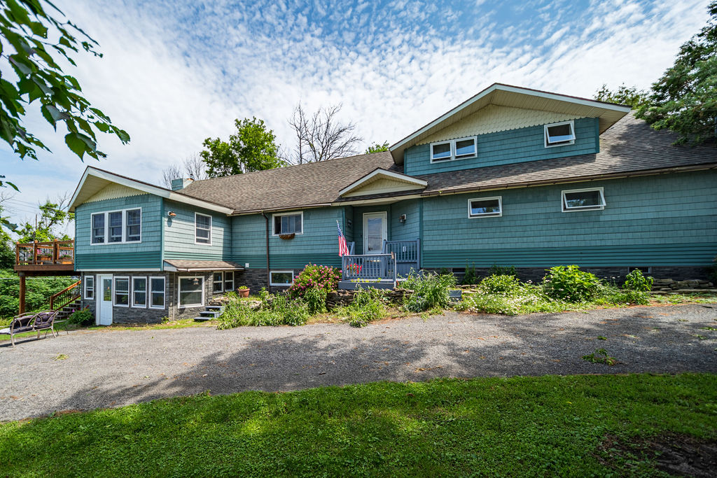 Rear exterior of the teal home with covered entry and gardens