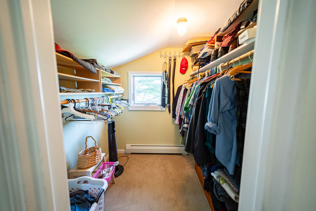 Large walk-in closet with built-in shelving and window