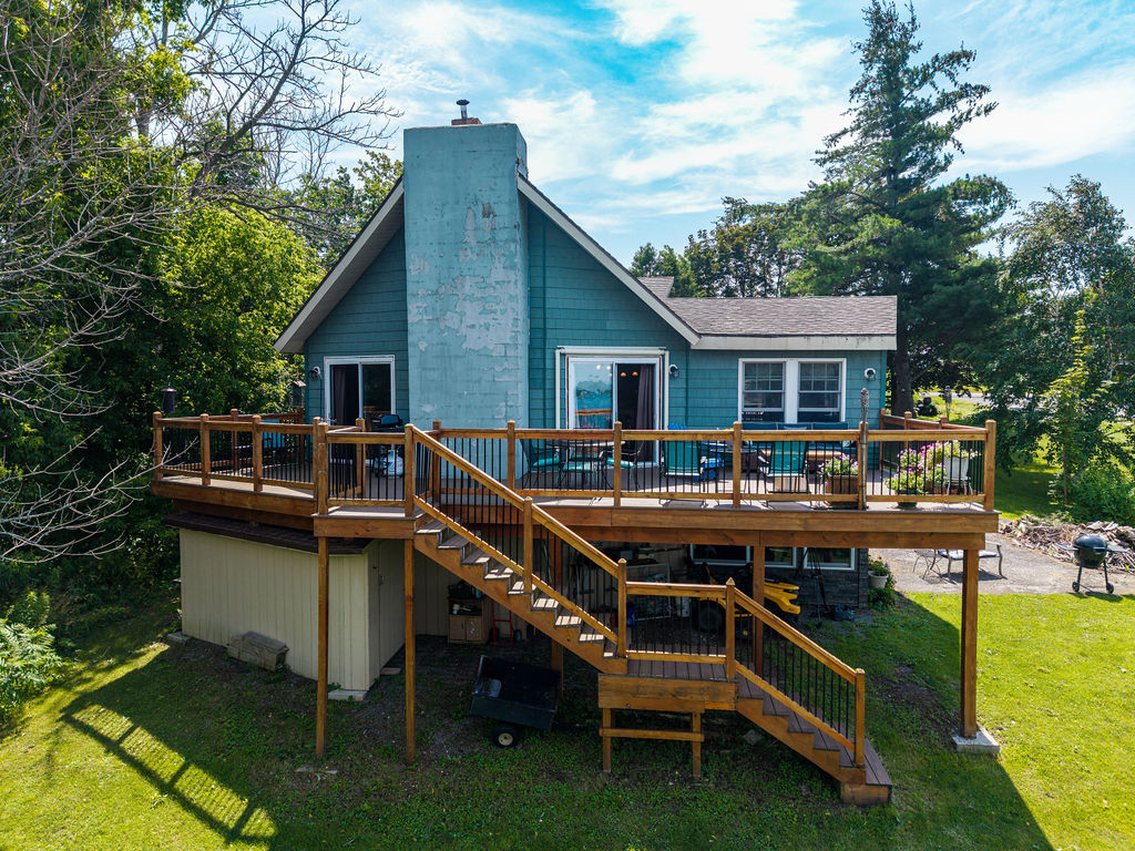 Rear of the home with expansive two-level Trex deck and stone chimney