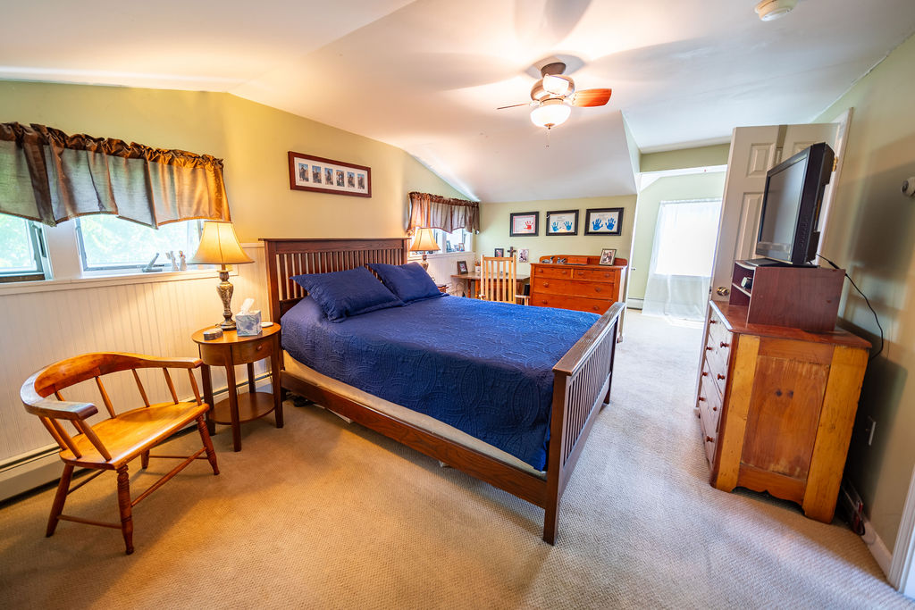 Spacious bedroom with queen bed, ceiling fan and sitting area