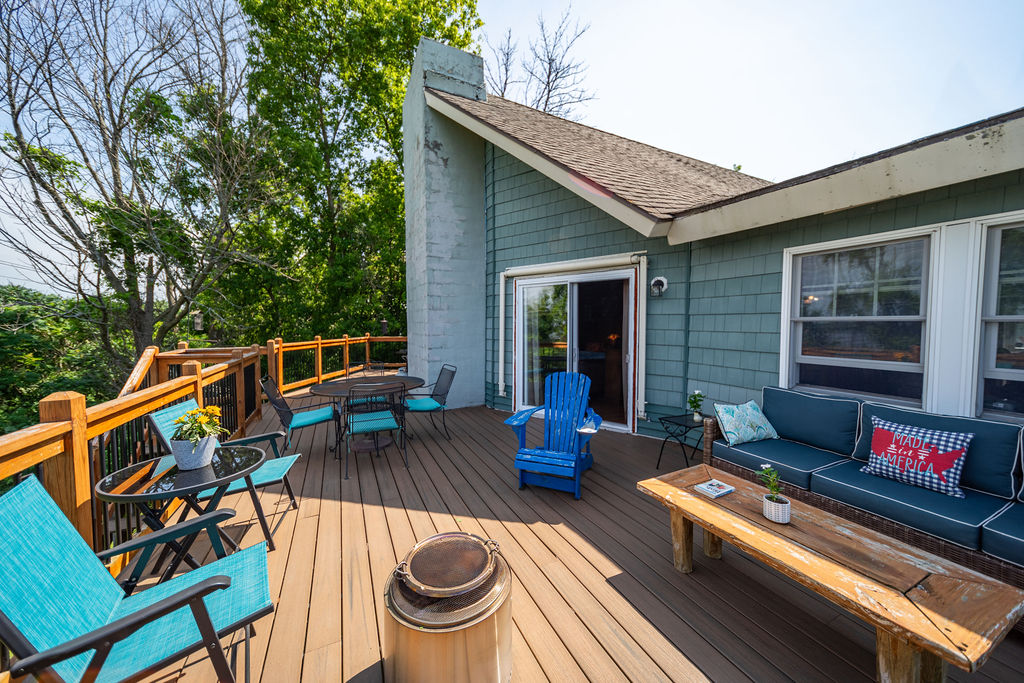 Trex deck with lounge sofa, dining set and fire pit overlooking the trees