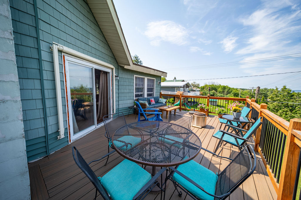 Deck dining area with turquoise chairs and sliding-door access to the home
