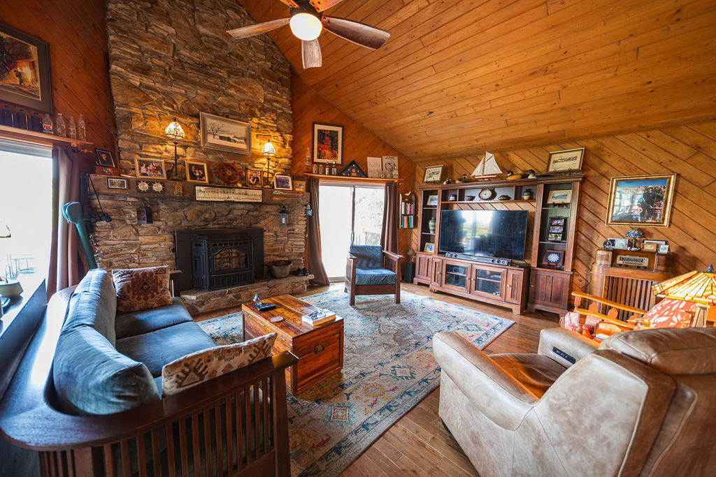 Living room with floor-to-ceiling stone fireplace and cathedral wood ceiling
