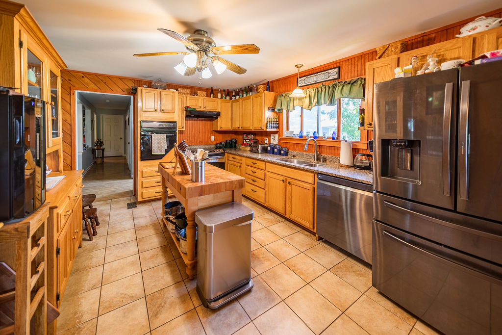 Wood kitchen with granite counters, butcher-block island and stainless fridge