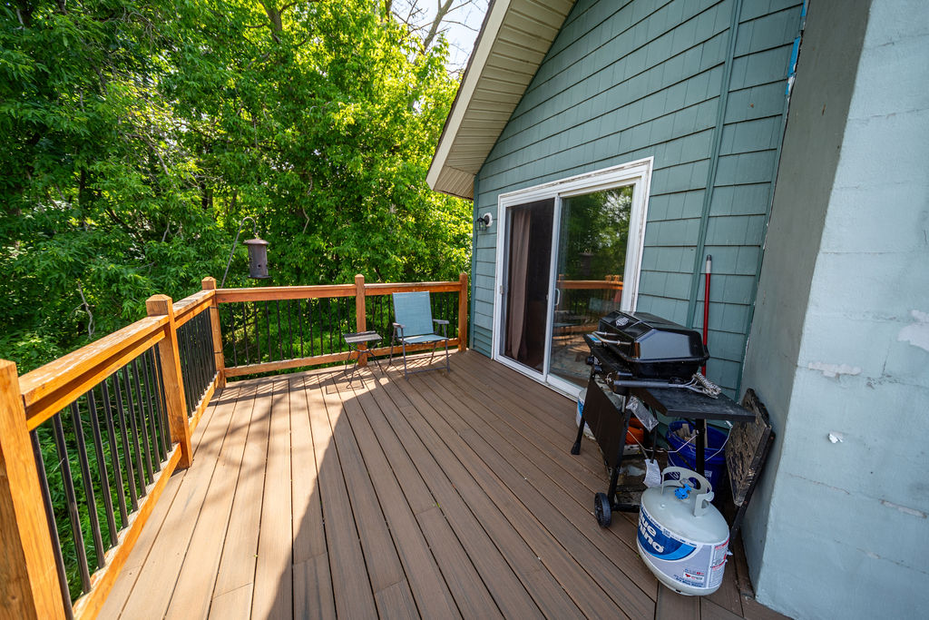 Side deck with grill and sliding-door access surrounded by trees