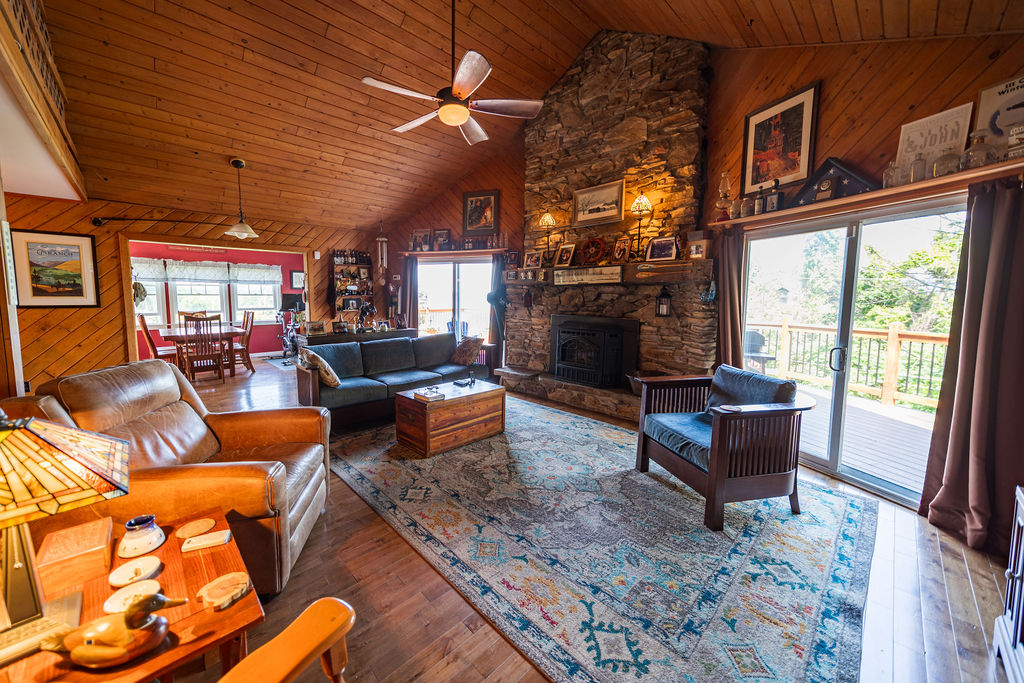 Open living room with stone fireplace, sliding doors to the deck and river views